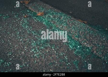 Stücke von gebrochenem grün getöntem Autoglas als Reste eines Einbruchs. Reste eines Einbruchs im Auto, Glasstücke auf der Straße oder auf dem Bürgersteig. Stockfoto