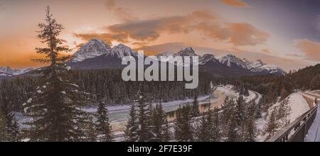 Panorama der berühmten Morant Kurve in der Nähe von Lake Louise in Alberta, Kanada an einem schönen sonnigen Winterabend. Spuren neben einem Fluss sind zu sehen. Stockfoto