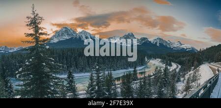 Panorama der berühmten Morant Kurve in der Nähe von Lake Louise in Alberta, Kanada an einem schönen sonnigen Winterabend. Spuren neben einem Fluss sind zu sehen. Stockfoto