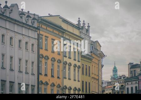 Eine Reihe von Häusern in Krakau, Polen. Typische Häuser im Stadtzentrum von Krakau, bunte Fassaden in einer Reihe leicht in einer Kurve auf einem grauen verschwinden Stockfoto