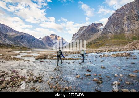 Backpacker navigieren sich über einen Fluss im Akshayuk Pass. Stockfoto