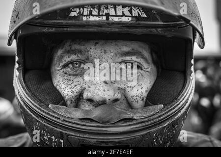 Nahaufnahme eines Mannes, der ein Ruder trägt, das von Schlamm bedeckt ist.DAS Gesicht EINES Mannes war nach einer Motorradsitzung von schlammigen Flecken bedeckt. Stockfoto