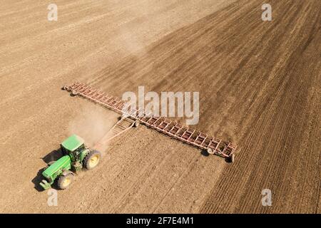 Der Traktor kultiviert die Bodenansicht von der Drohne aus Stockfoto