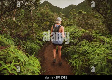 Fit blonde Frau zu Fuß auf einem Bergpfad in O'ahu Stockfoto