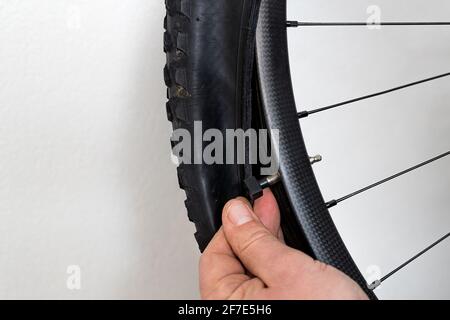 Reparatur von Fahrradschlauchs. Eine Hand einer Person installiert ein presta-Ventil an einem schlauchlosen Carbon-Mountainbike-Rad. Stockfoto