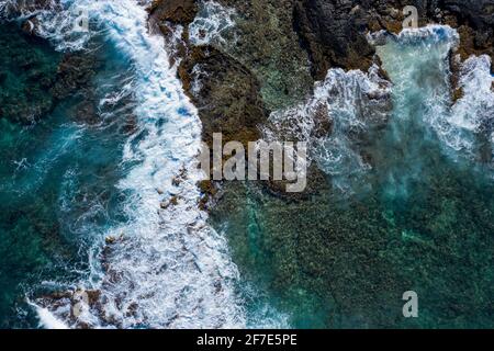 Drohnenfoto von Ozeanwellen, die auf braunen Felsen in aufprallen Hawaii Stockfoto