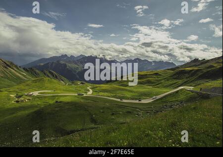 Panorama vom Großglockner-Pass am Hochtor an einem Sommertag mit schönen Wolken, grünen Wiesen und kurviger Straße unten gesehen. Sommer auf Bergpass. Stockfoto