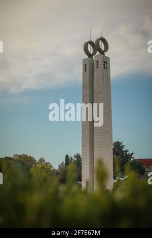 Denkmal der Nelkenrevolution in Lissabon, ein Obelisk im Park von Eduardo VII in Lisbona, Portugal. Türme, die aus grünem Gras im Park emporragen. Stockfoto