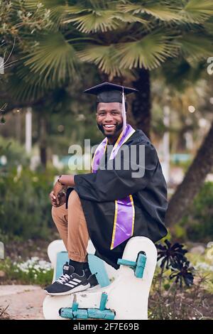 Ich freue mich, das College zu graduiert zu haben, der Mann trägt ein Abschlusskleid/Mütze. Stockfoto