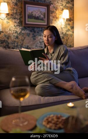 Asiatische Frau liest am Abend ein Buch Stockfoto