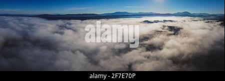 Am frühen Morgen Drohnenpanorama des Planinsko Polje Feldes in Slowenien während des dichten Nebels über der Ebene, mit nur höheren Hügeln wie Slivnica gesehen werden st Stockfoto