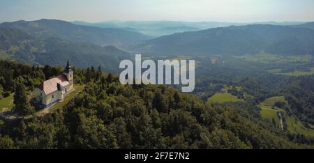 Panorama von Sveti Miklavz oder St. Nikolaus Kirche auf der Spitze des Hügels oberhalb von Kresnice im Sava-Tal in Slowenien an einem Sommermorgen Stockfoto