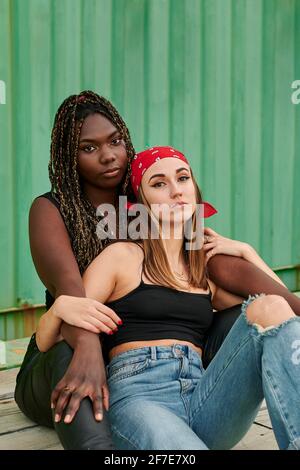 Multiethnische Frauen, die sich in Stadtkleidung umarmen, posieren vor der Kamera Stockfoto