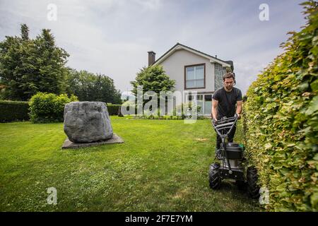 Kabelverlegungsmaschine mit einem Bediener, der die Kabel für Mähroboter ablegt. Einstecken des Kabels in den Boden als Führungskabel für Roboterlawnm Stockfoto