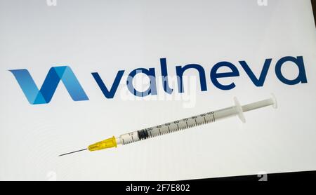 Valneva COVID-19 Impfstoffkonzept. Spritze und Valneva Firmenlogo auf dem unscharfen Hintergrundbildschirm. Stafford, Großbritannien, 6. April 2021. Stockfoto