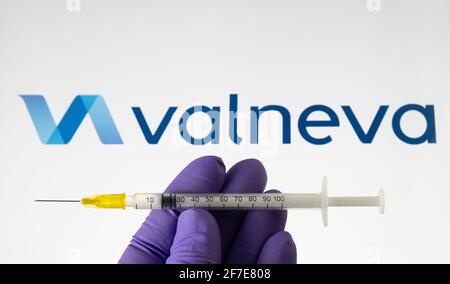 Valneva COVID-19 Impfstoffkonzept. Spritze und Valneva Firmenlogo auf dem unscharfen Hintergrundbildschirm. Stafford, Großbritannien, 6. April 2021. Stockfoto