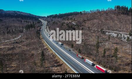 Stau auf der Autobahn oder Autobahn. Luftdrohnenaufnahme von Lastwagen oder Lastwagen, die in einem Stau über dem Land stecken. Lange Schlange von Sattelaufliegern o Stockfoto