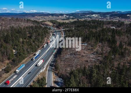 Stau auf der Autobahn oder Autobahn. Luftdrohnenaufnahme von Lastwagen oder Lastwagen, die in einem Stau über dem Land stecken. Lange Schlange von Sattelaufliegern o Stockfoto