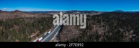 Stau auf der Autobahn oder Autobahn. Luftdrohnenaufnahme von Lastwagen oder Lastwagen, die in einem Stau über dem Land stecken. Lange Schlange von Sattelaufliegern o Stockfoto