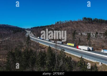 Stau auf der Autobahn oder Autobahn. Luftdrohnenaufnahme von Lastwagen oder Lastwagen, die in einem Stau über dem Land stecken. Lange Schlange von Sattelaufliegern o Stockfoto