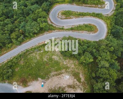 Kurvenreiche Straße oder Serpentinen über dem Dorf Osilnica in der Nähe von Borovec in Slowenien an einem kalten bewölkten Morgen. Der Van ist auf dem Parkplatz zu sehen. Schöner Stockfoto