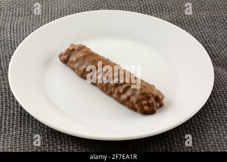 Schokoladen-Süßigkeitenbar mit Puffreis und Karamell Weiße Platte auf grauem Grat Stockfoto