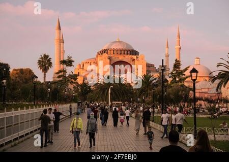 ISTANBUL, TÜRKEI - 09 07 2020: Menschen gehen im Sultan Ahmet Park vor der Hagia Sophia Kathedrale Moschee Basilika beleuchtet mit warmen Sonnenstrahlen bei Sonnenuntergang Stockfoto