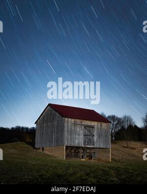 Star trails over an old barn in a field on the outskirts of Shenandoah National Park in Virginia. Stockfoto