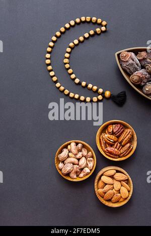 Ramadan Kareem und iftar muslimisches Essen, modernes Urlaubskonzept. Holzschalen mit Nüssen und getrockneten Früchten und der Mond aus Perlen Stockfoto