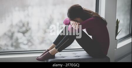 Traurige weinende junge Frau, die sich in Traurigkeit allein zu Hause in Isolation versteckt. Psychische Gesundheit Problem soziale Angst Panikattacke ptsd Auswirkungen von der Stockfoto