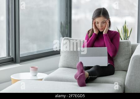 Computerproblem Laptop funktioniert nicht zu Hause frustrierte asiatische Frau mit Kopfschmerzen versuchen, Online-Arbeit oder Problem zu verstehen. Stockfoto