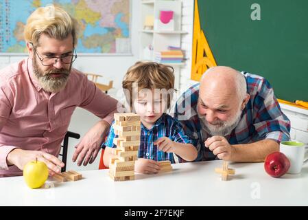 Jenga Spiel zu Hause. Glückliche Generationenmuti drei Generationen Männer Familienportrait. Mann in verschiedenen Altersgruppen. Stockfoto