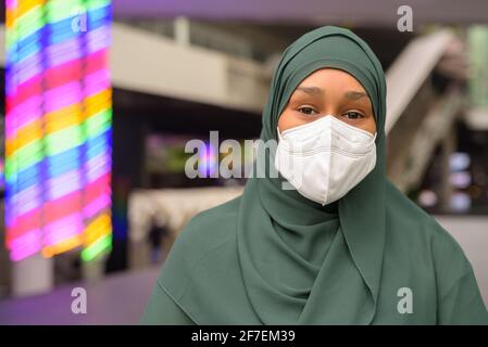 Schöne schwarze afrikanische muslimische Frau trägt Gesichtsmaske im Freien Stockfoto
