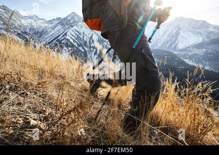 Mann Tourist mit Rucksack ist zu Fuß im Herbst Bergtal mit schneebedeckten Gipfeln in Almaty, Kasachstan Stockfoto