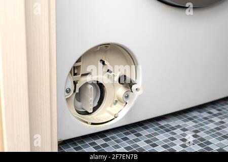 Der Filter der Waschmaschine ist verstopft. Filterdeckel der Waschmaschine öffnen. Problem mit dem Wäschewaschen. Stockfoto