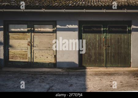 Zwei alte Garagentore aus Holz in grüner Farbe. Grün gefärbte Farbe an der Holztür, mit Vorhängeschlössern verschlossen. Stockfoto