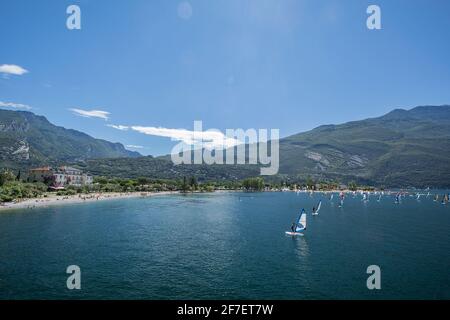 Eine Vielzahl von Windsurfern an einem sonnigen Tag am Gardasee vor Torbole riva in Aktion. Stockfoto