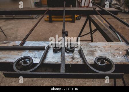 Schmiede, in der ein Teil eines Geländers hergestellt und auf einer stabilen Arbeitsfläche aus Metall miteinander verschweißt wird. Stockfoto