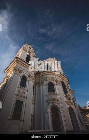 Fassade der kollegienkirche in Salzburg, die an einem trüben, grauen Herbsttag von unten auf einen der Glockentürme blickt. Stockfoto