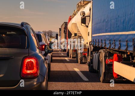 Lange Schlange von Lastwagen und Autos als Teil eines Staus auf einer Autobahn in italien, europa an einem sonnigen Tag. Stockfoto