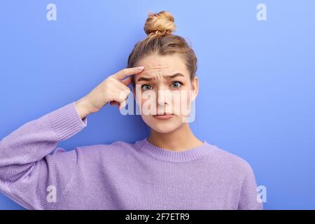 Nachdenkliches Mädchen mit Haarbüschen, das unzufrieden Grimasse macht, als ob es Nein sagen würde, das ist keine Option, während es versucht, das Problem zu lösen, über die Entscheidung nachzudenken, touc Stockfoto