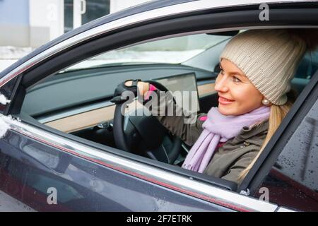 MINSK. WEISSRUSSLAND - JANUAR 2021: Eine schöne Frau schaut aus dem Fenster eines Elektroautos. Stockfoto