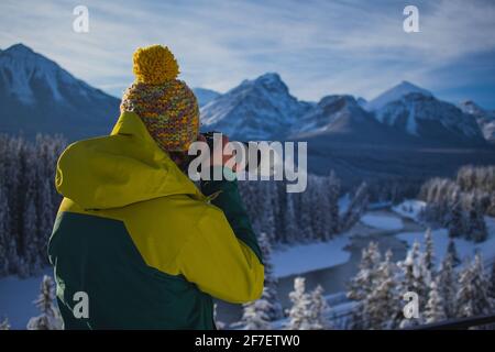 Ein Mann fotografiert wunderschöne schneebedeckte Berglandschaften. Mann in Winterkleidung und Teleobjektiv, der Fotos von einer wunderschönen Berglandschaft gemacht hat. P Stockfoto