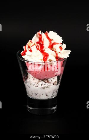 Heiße Schokolade oder Kaffee Getränk in Glas-Tasse mit Halter, isoliert auf schwarz. Sichtbare Kokosnüsse, Milch, Schlagsahne und andere süße Zutaten Stockfoto