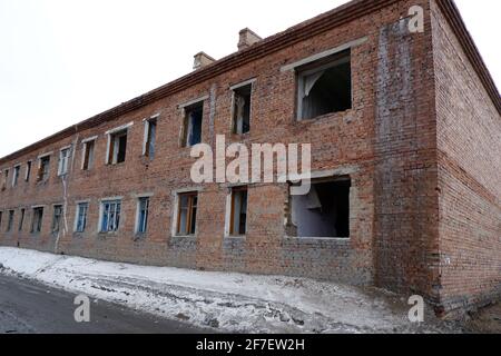 Ein altes, heruntergekommenes Ziegelhaus mit kaputten Fenstern. Stockfoto