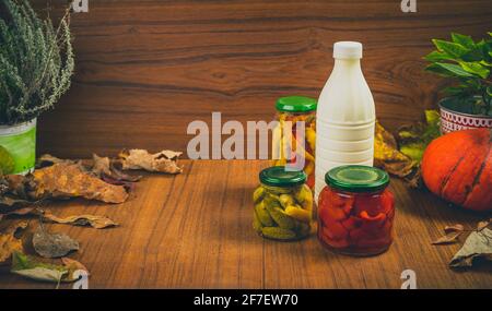 Überwintern von saisonalen Produkten in Gläsern wie Gurken, Paprikas, Paprika in einem Herbstdisplay auf einem Holztisch und an einer Wand. Speicherplatz auf dem kopieren Stockfoto