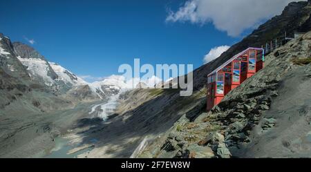 Rote Standseilbahn auf dem Großglockner, direkt hinter dem Pasterze-Gletscher im Hintergrund an einem warmen, sonnigen Tag mit blauem Himmel im Summe Stockfoto