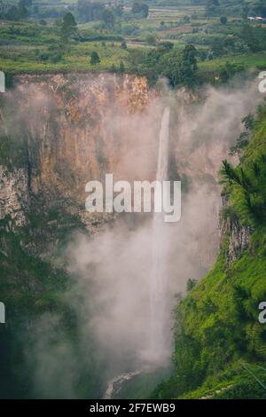 Vertikales Foto von Sipisopiso ein Wasserfall im Batak-Hochland von Sumatra, Indonesien an einem bewölkten Tag, während der regnerischen, grünen, feuchten Jahreszeit. Stockfoto