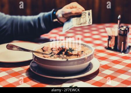 Eine Person zahlt seine Schüssel mit Lebensmitteln, die Kohl in einer Schüssel ist, mit 5 Euro Rechnung. Stockfoto