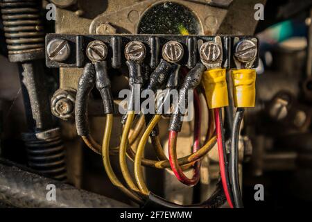 Verschiedene elektrische Anschlüsse an einer Anschlussdose an einem Außenbordmotor. Gelbe, rote und schwarze Drähte mit Schutzisolierung, die an einem Steckverbinder angeschlossen sind Stockfoto